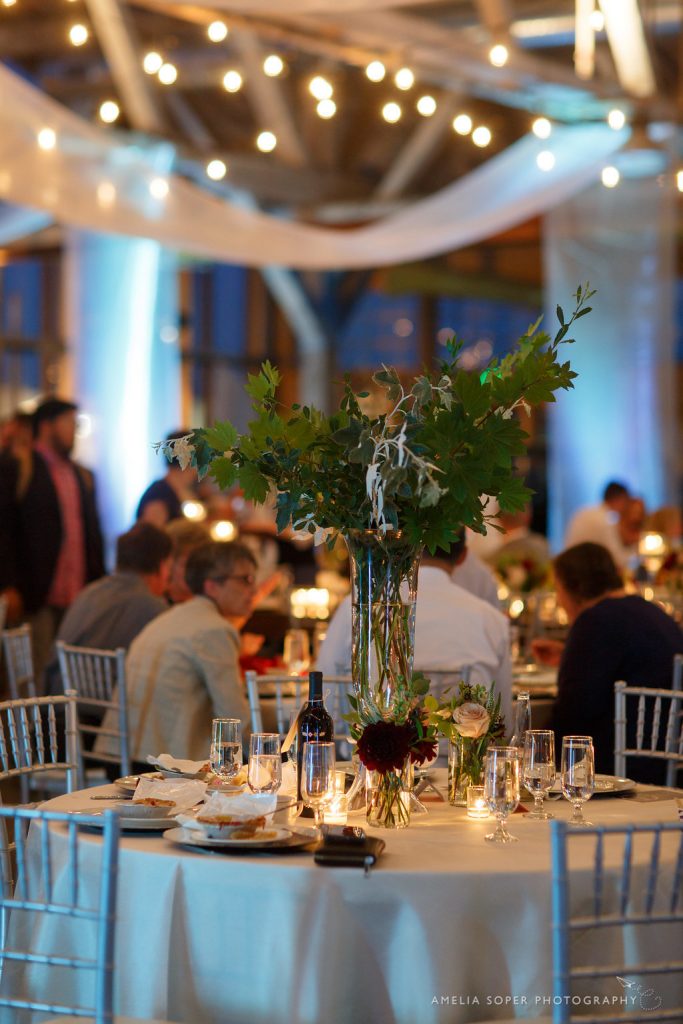 Elevated centerpiece of greens with accent vases of flowers by Jen's Blossoms