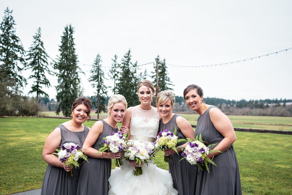 Bridesmaids in charcoal grey dresses carried bouquets of white, purple, and lavender flowers by Jen's Blossoms