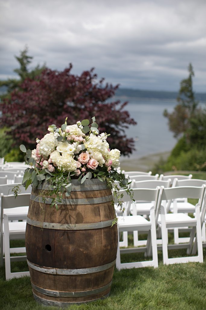 Wine barrel with arrangement of hydrangea, roses, and greens by Jen's Blossoms